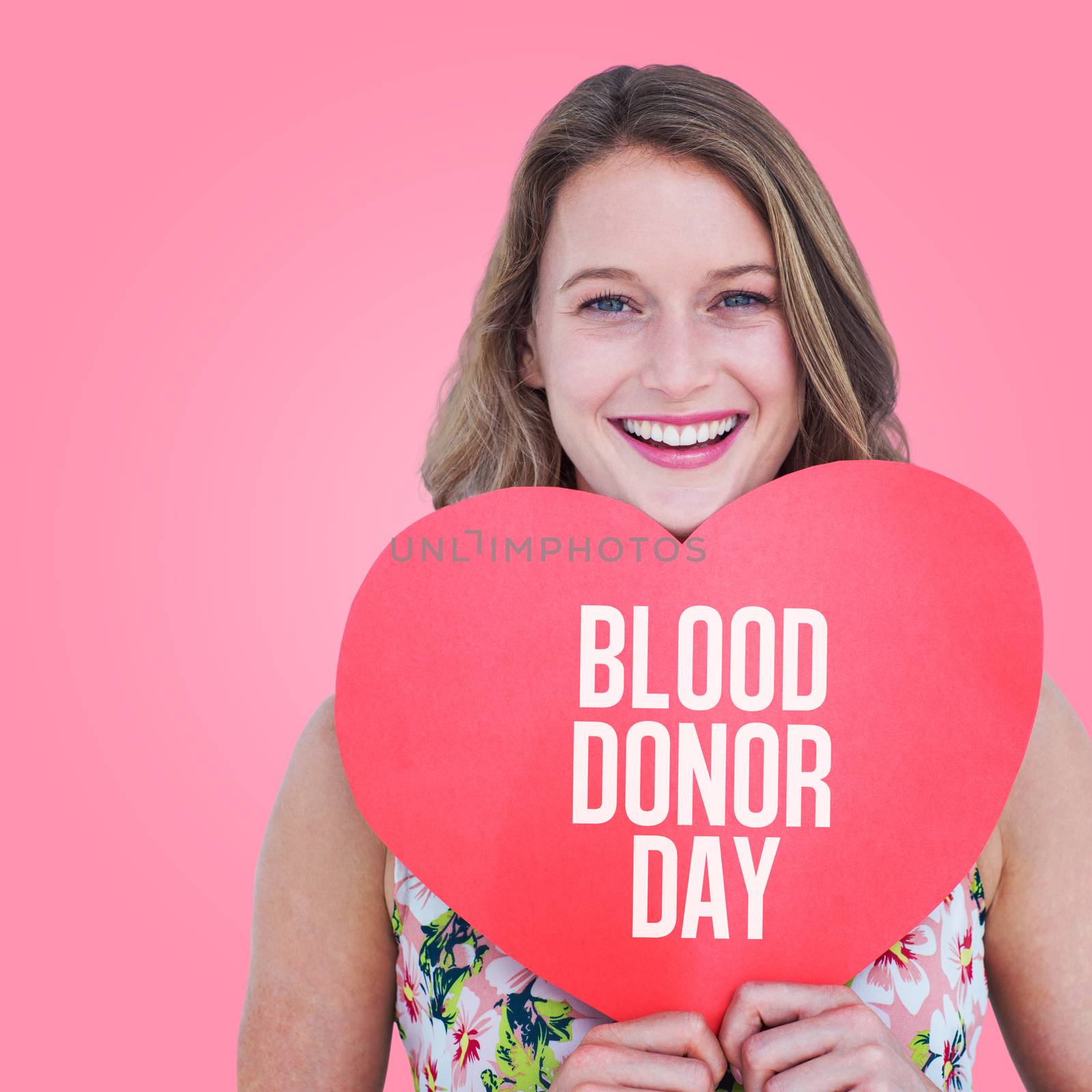 Woman holding heart card  against pink