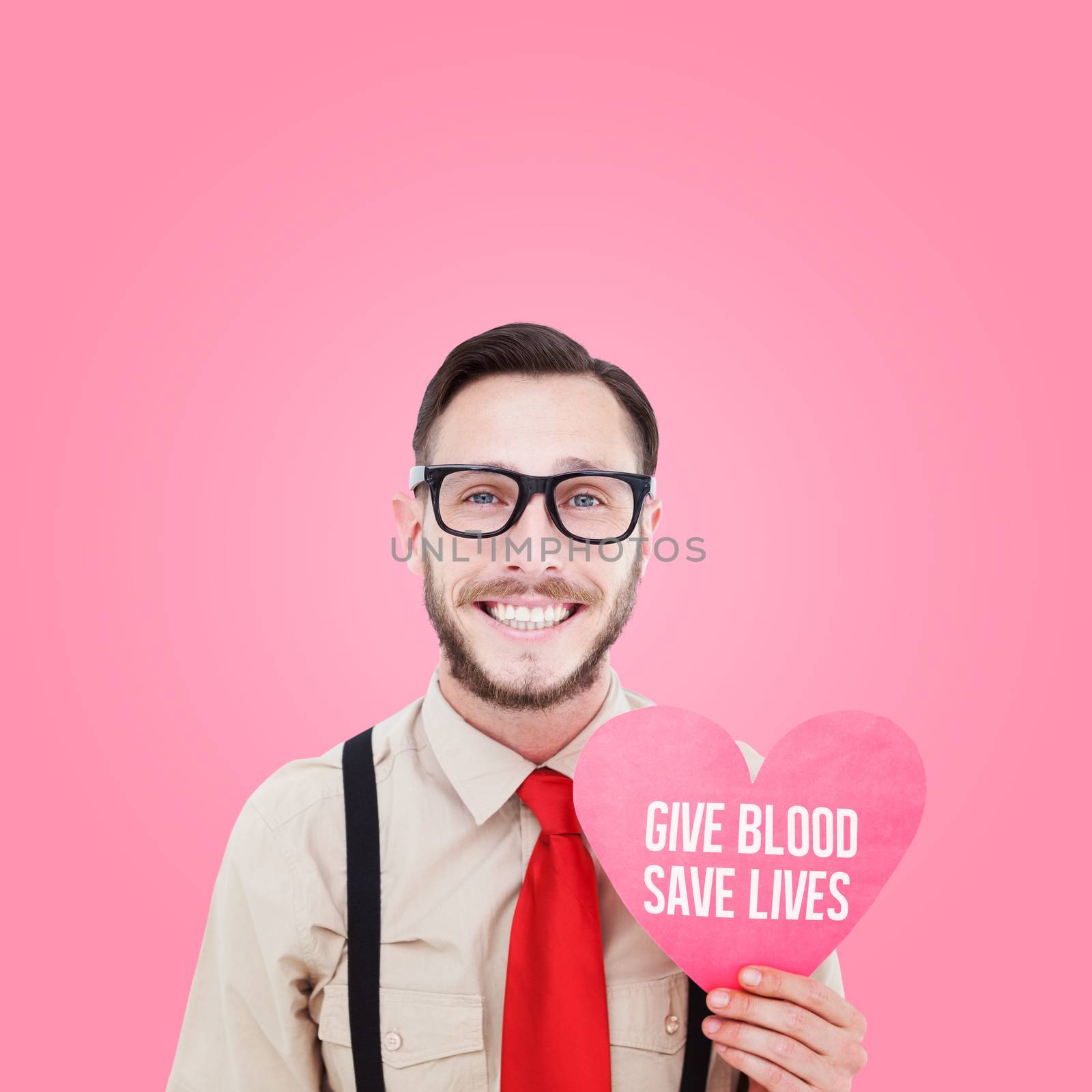 Geeky hipster smiling and holding heart card against pink