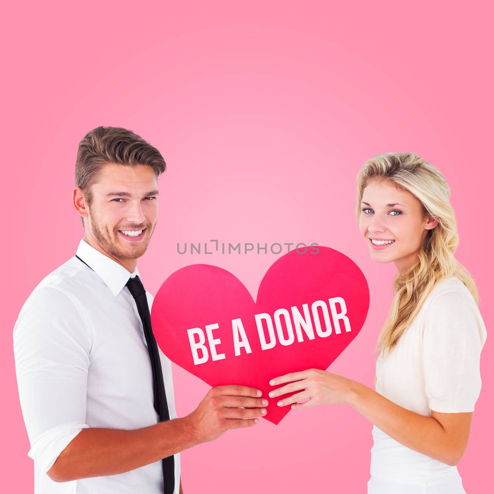 Attractive young couple holding red heart against pink