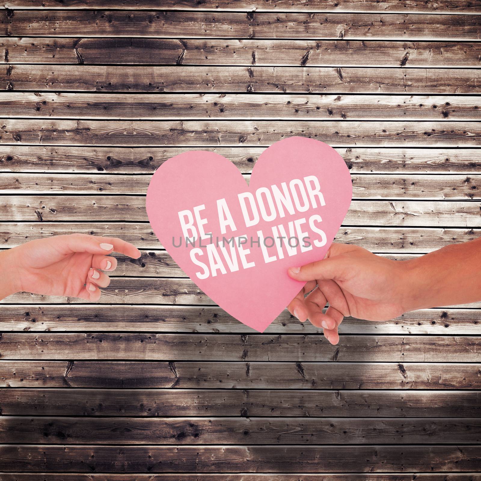 Couple passing a paper heart against wooden planks background