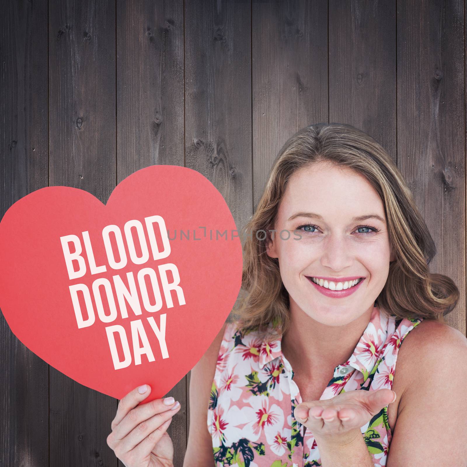 Composite image of woman holding heart card and blowing kiss by Wavebreakmedia