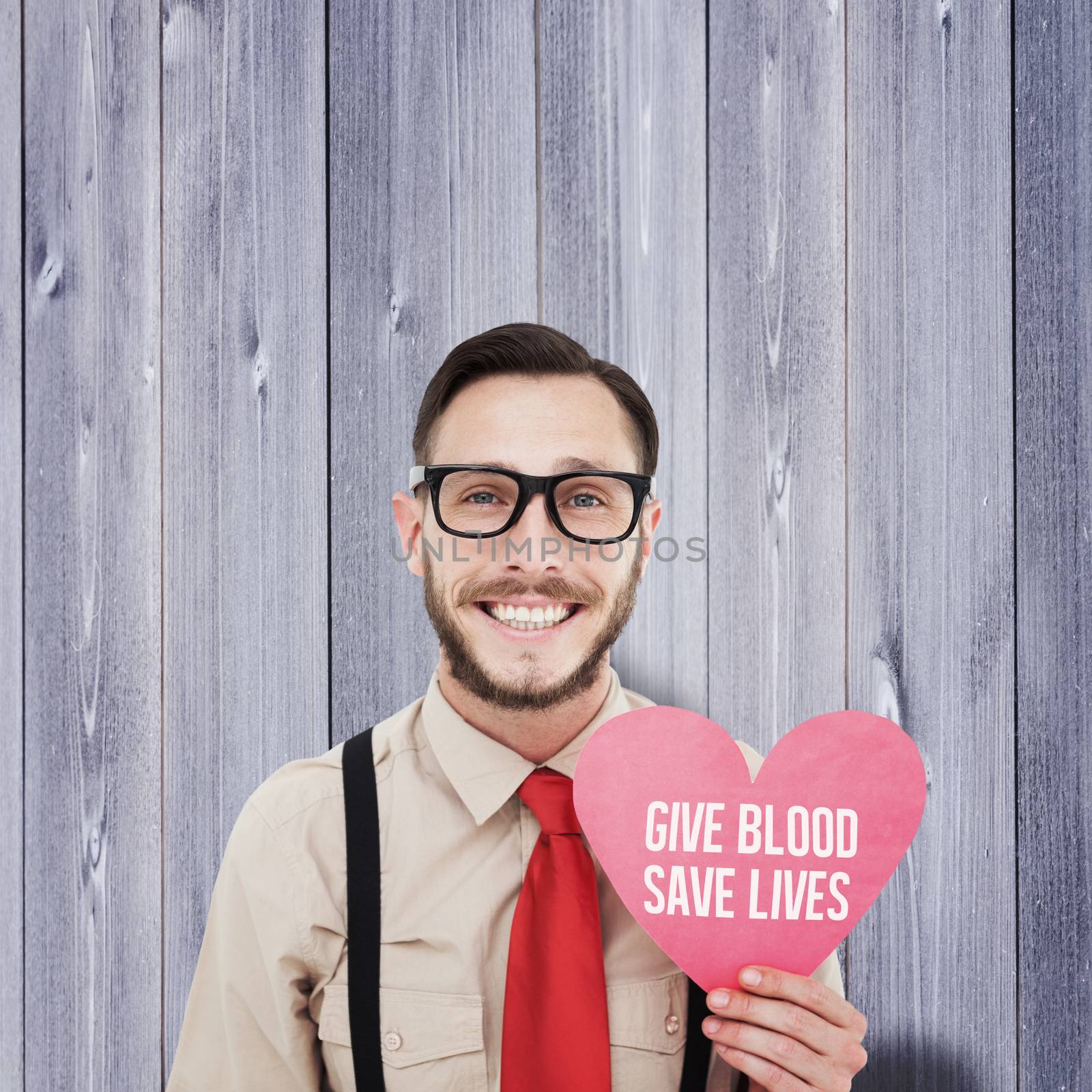Geeky hipster smiling and holding heart card against wooden planks