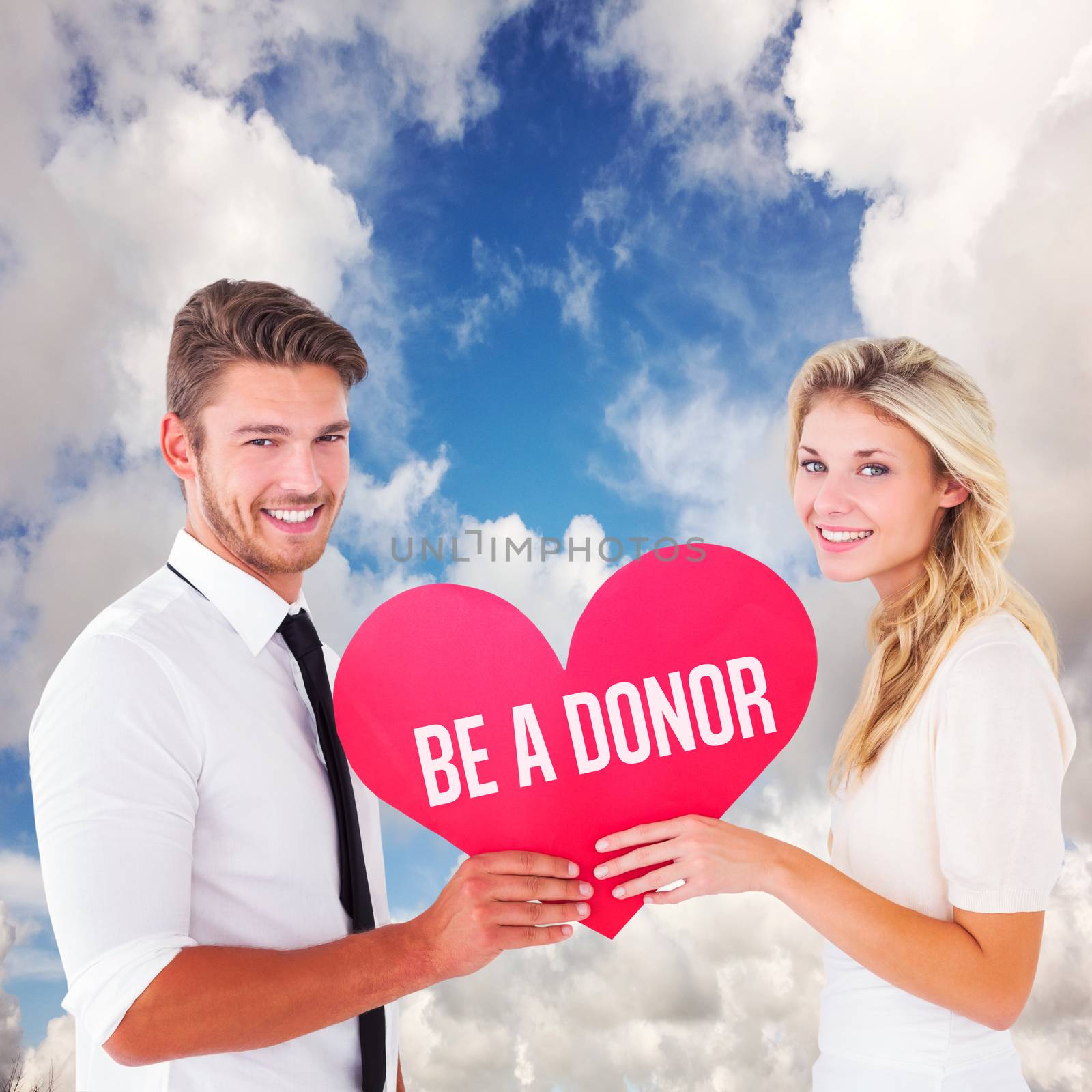 Attractive young couple holding red heart against blue sky with white clouds