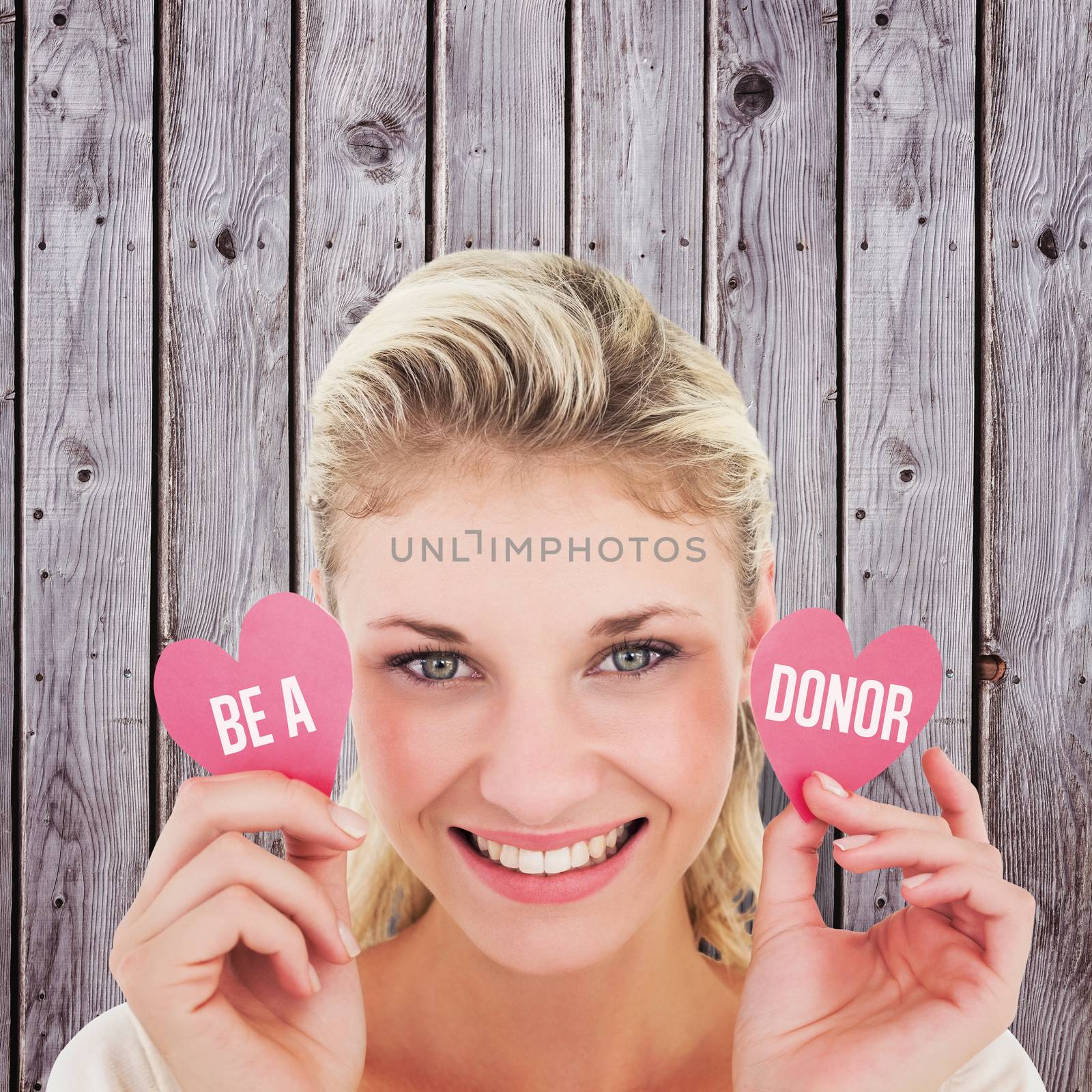 Attractive young blonde holding little hearts  against digitally generated grey wooden planks