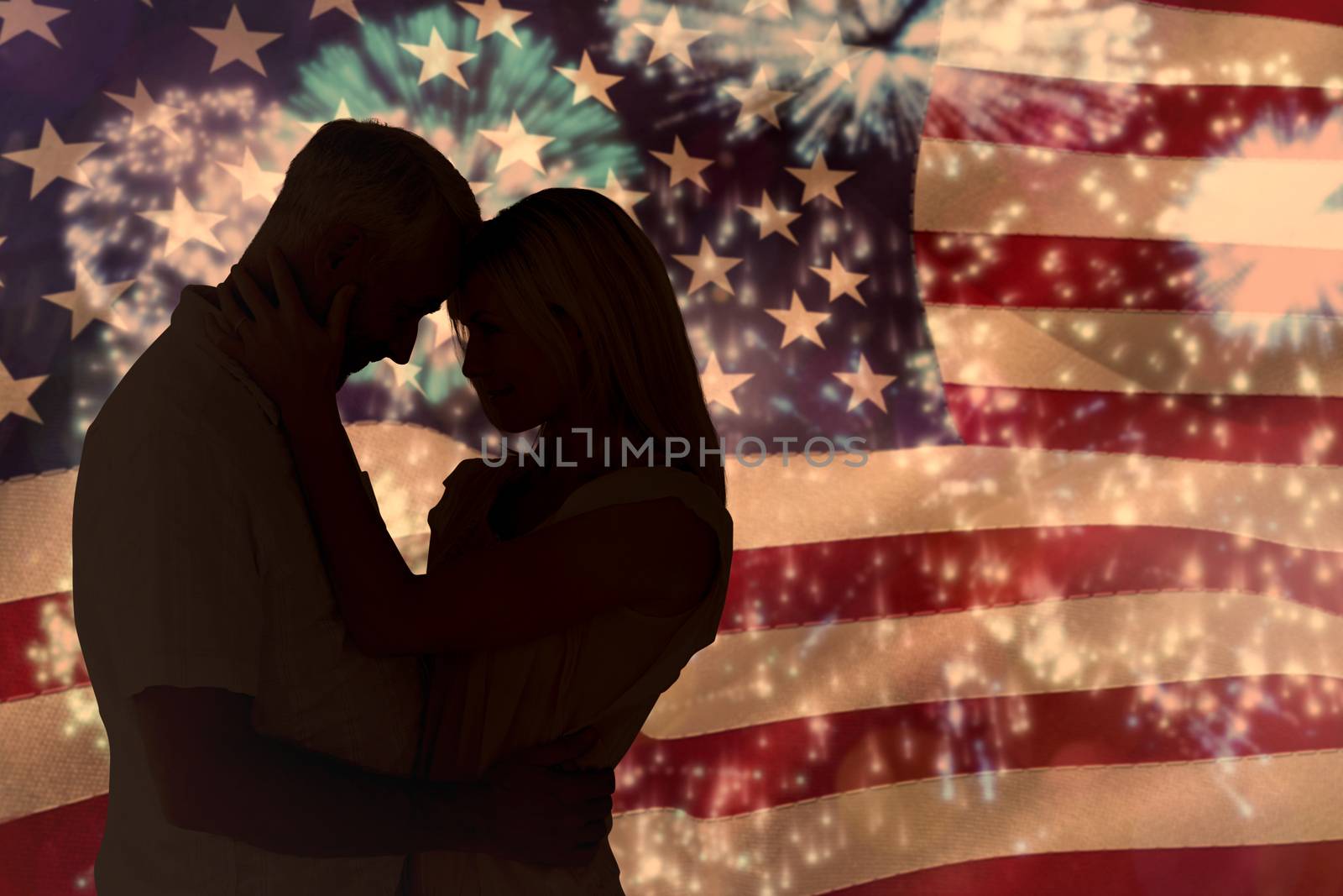 Affectionate couple standing and hugging against colourful fireworks exploding on black background