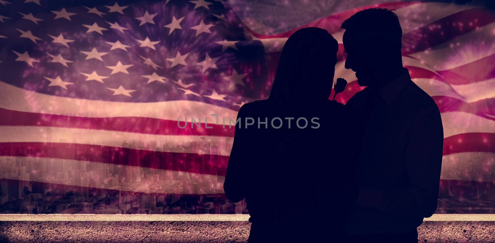 Handsome man giving his wife a pink rose against colourful fireworks exploding on black background