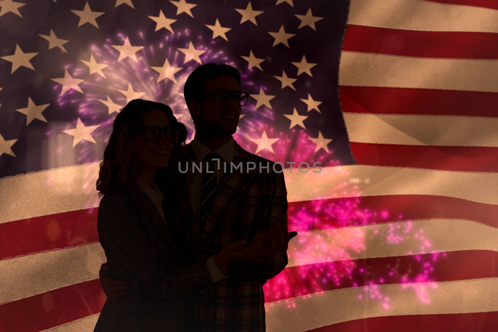 Geeky young hipster smiling at camera against colourful fireworks exploding on black background