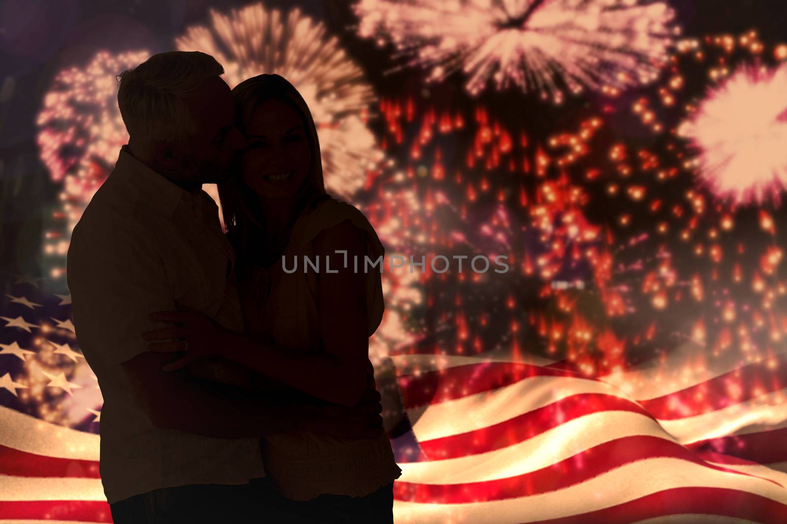 Affectionate man kissing his wife on the cheek against colourful fireworks exploding on black background
