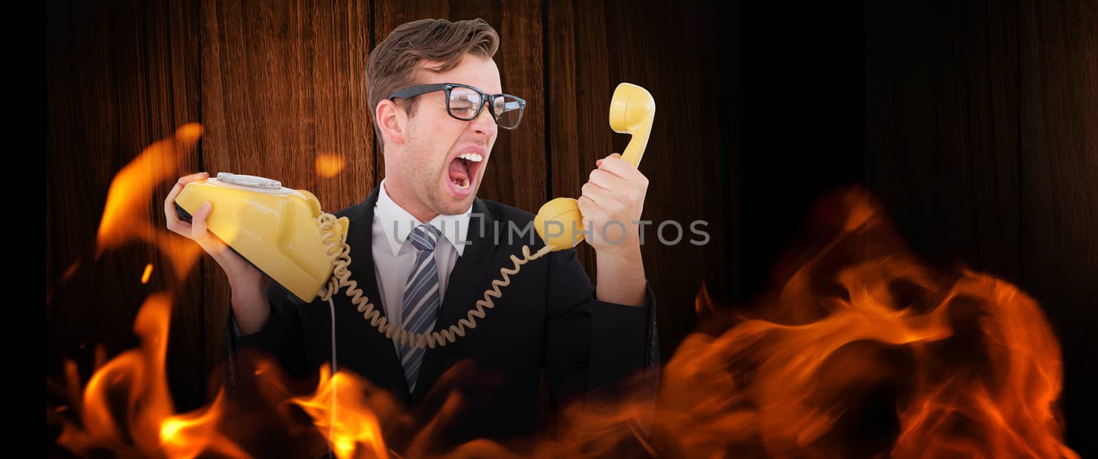 Geeky businessman shouting at telephone against wooden table