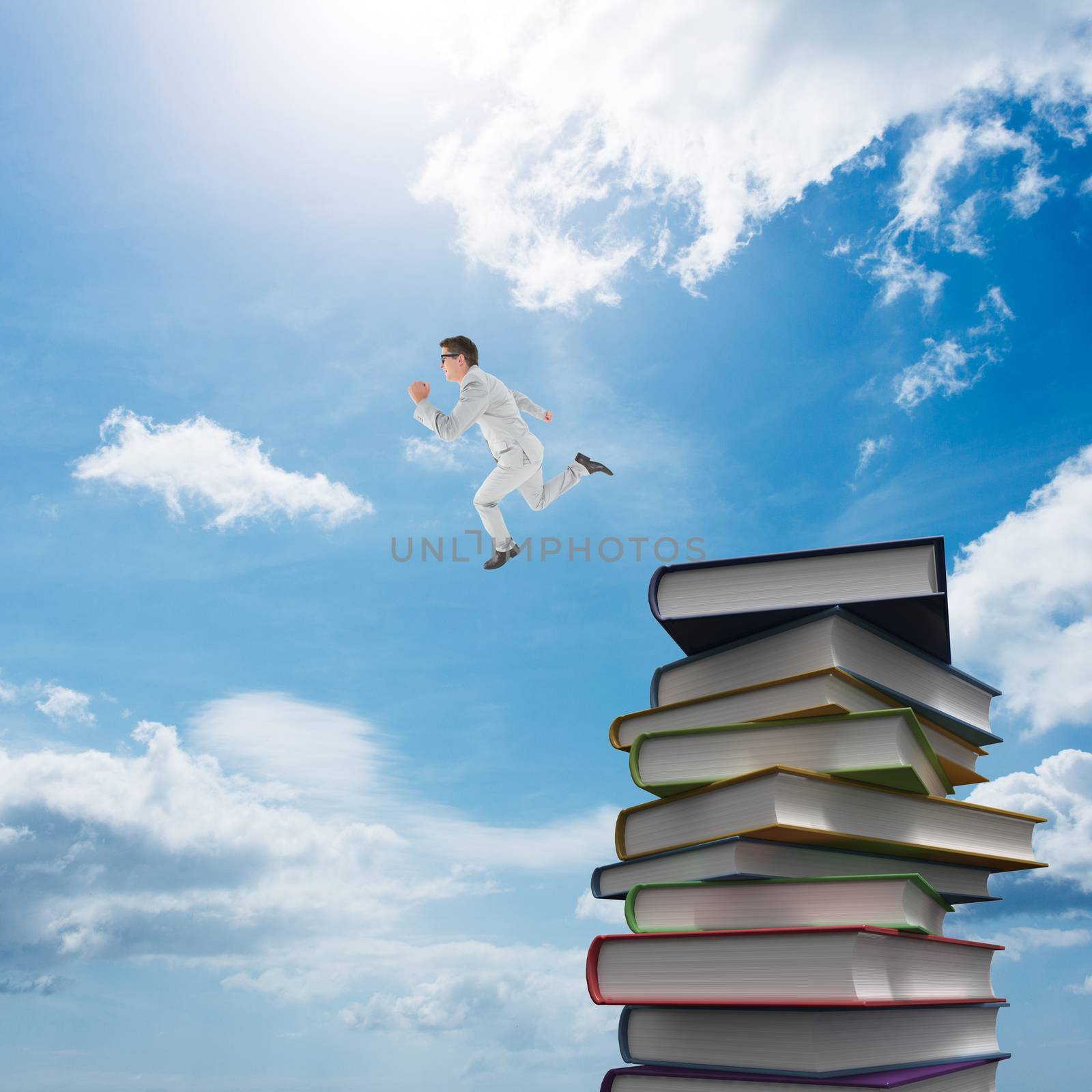 Geeky happy businessman running mid air against stack of books
