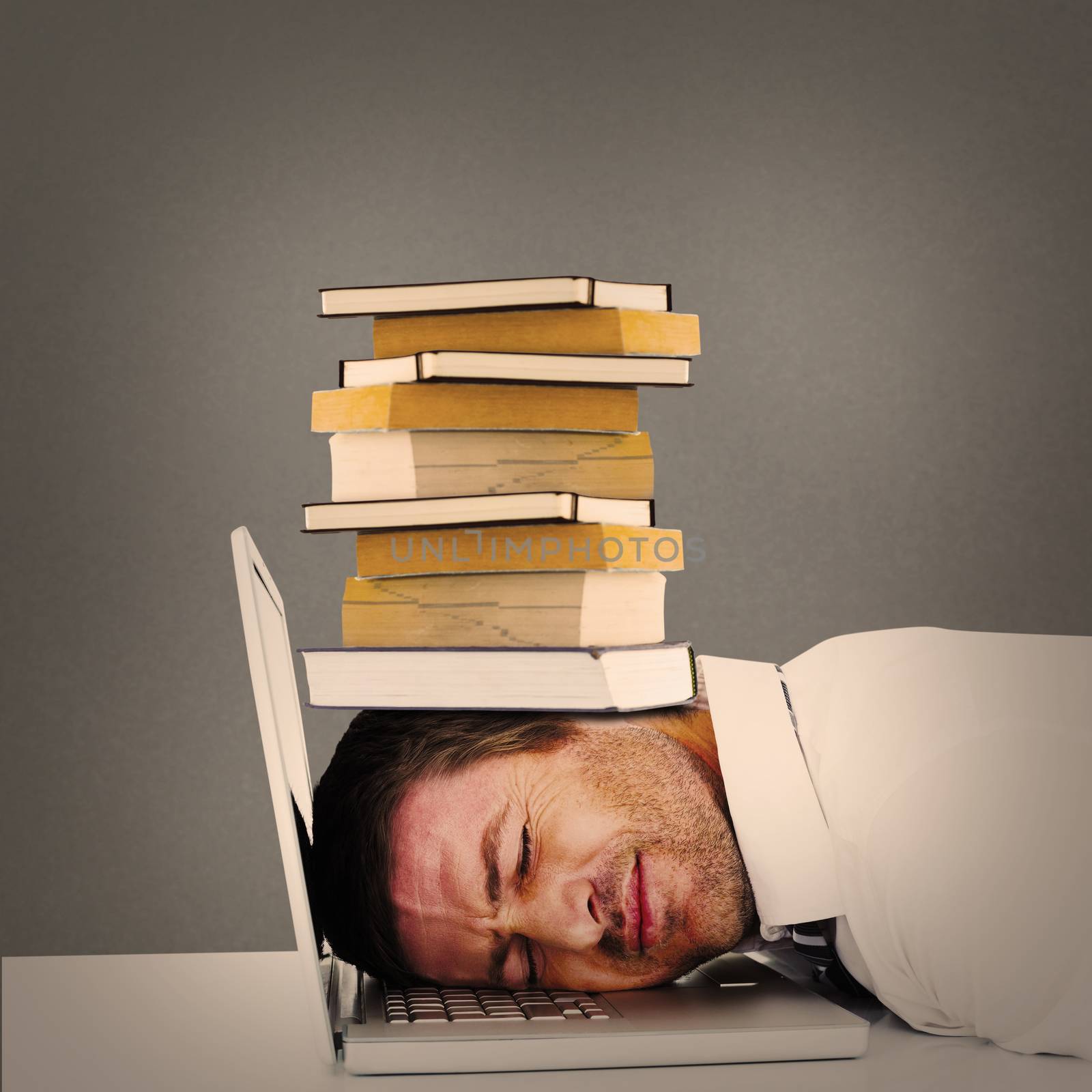 Tired businessman resting on laptop against grey background