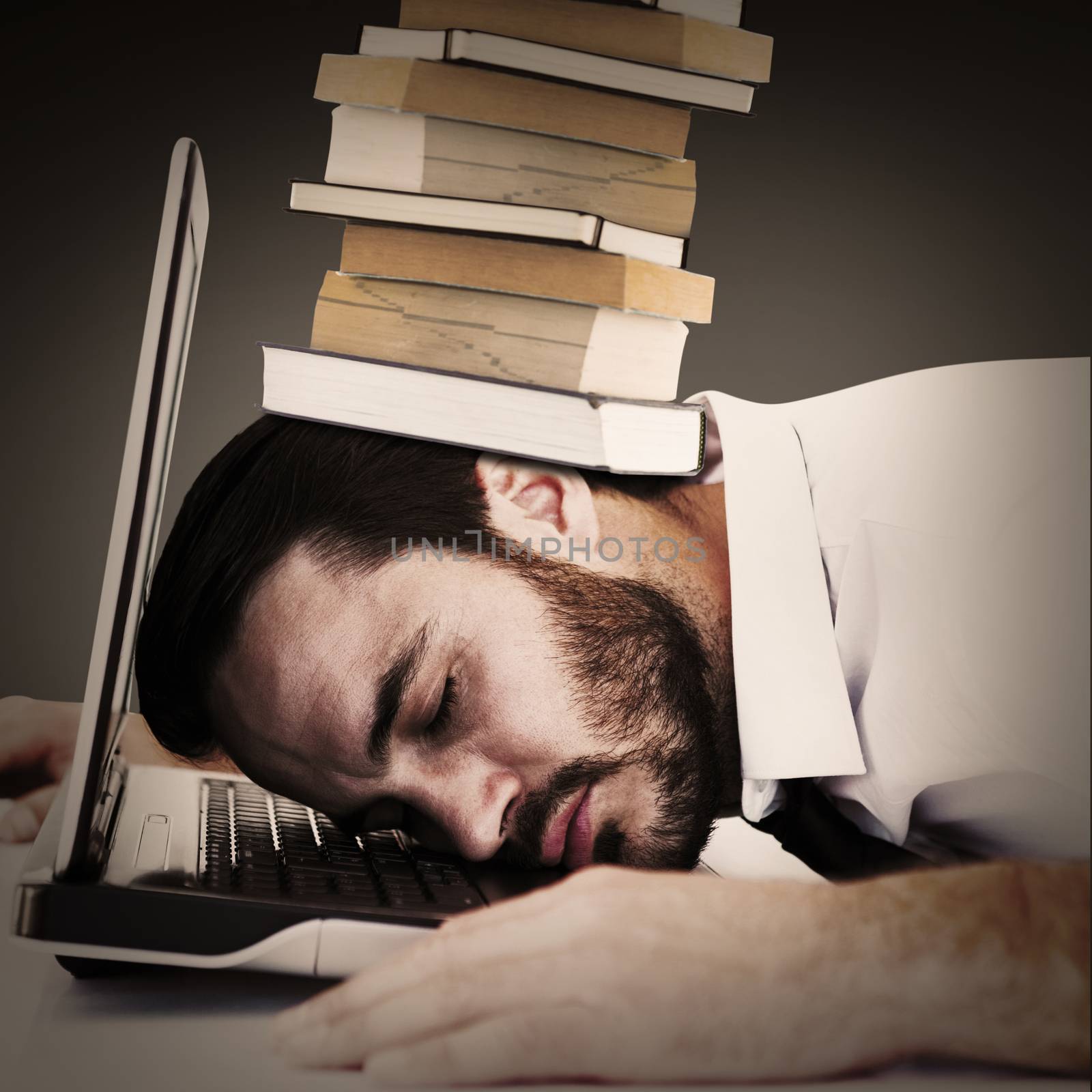 Businessman resting head on laptop keyboard against grey vignette