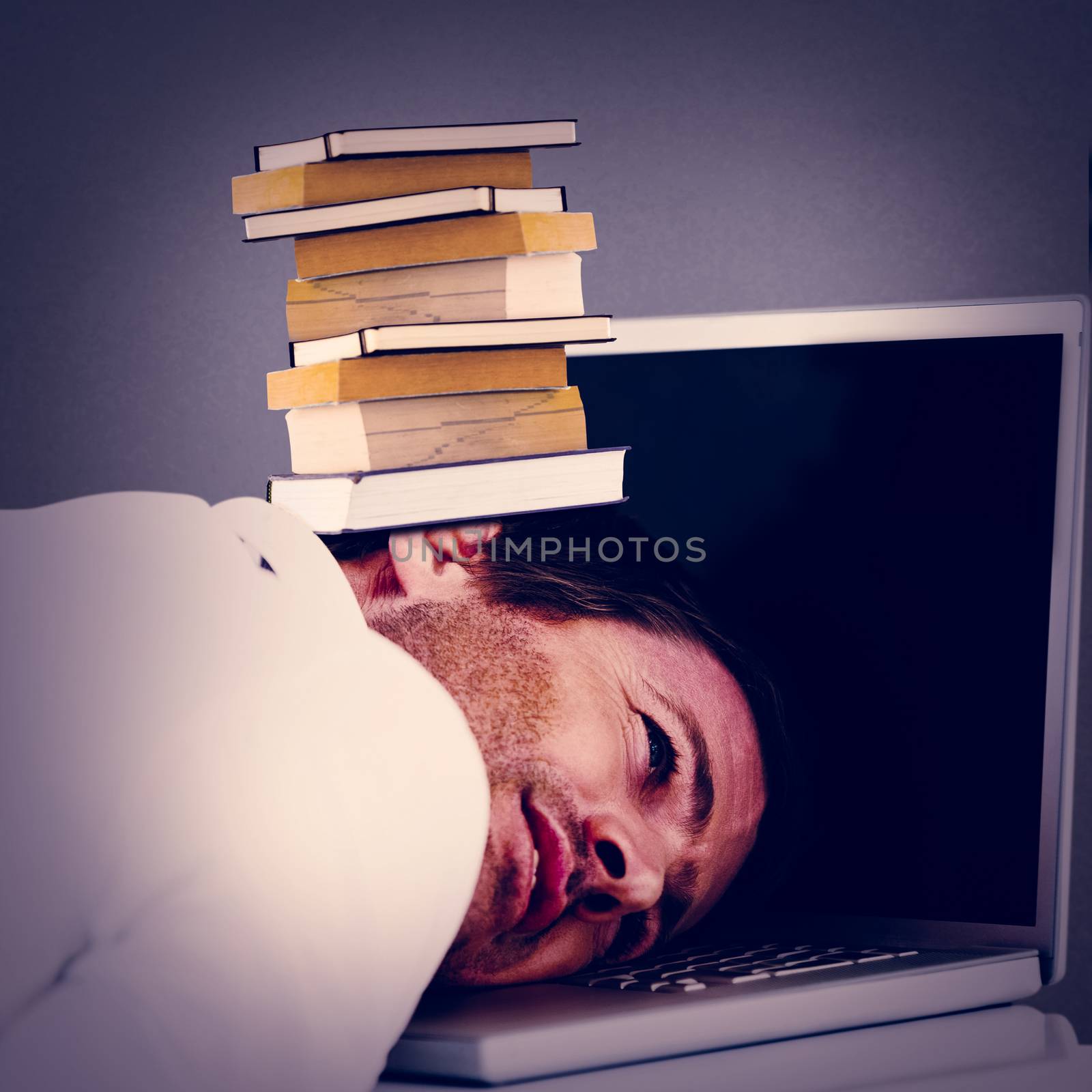 Businessman resting head on laptop keyboard against grey background