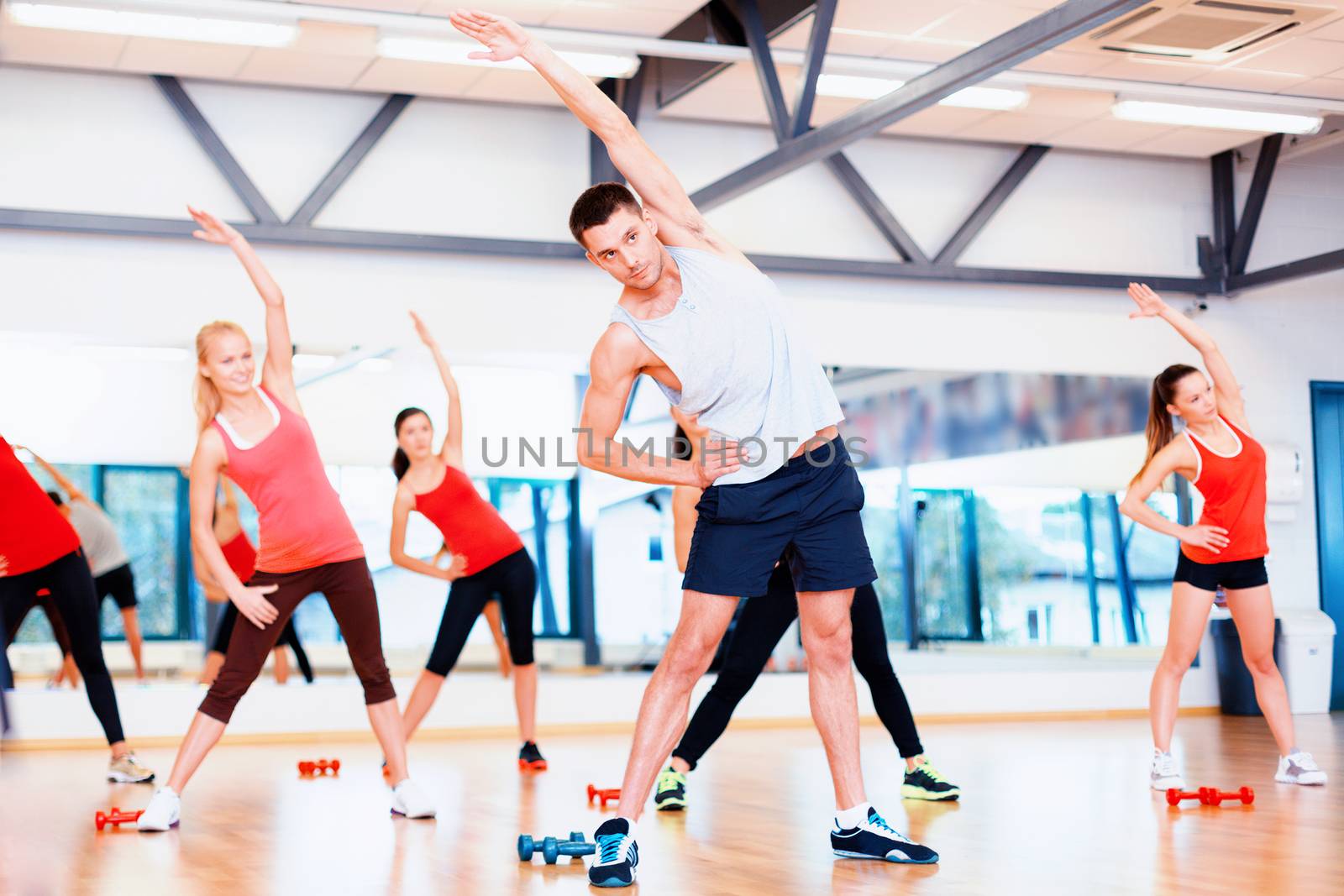 fitness, sport, training, gym and lifestyle concept - group of smiling women stretching in the gym