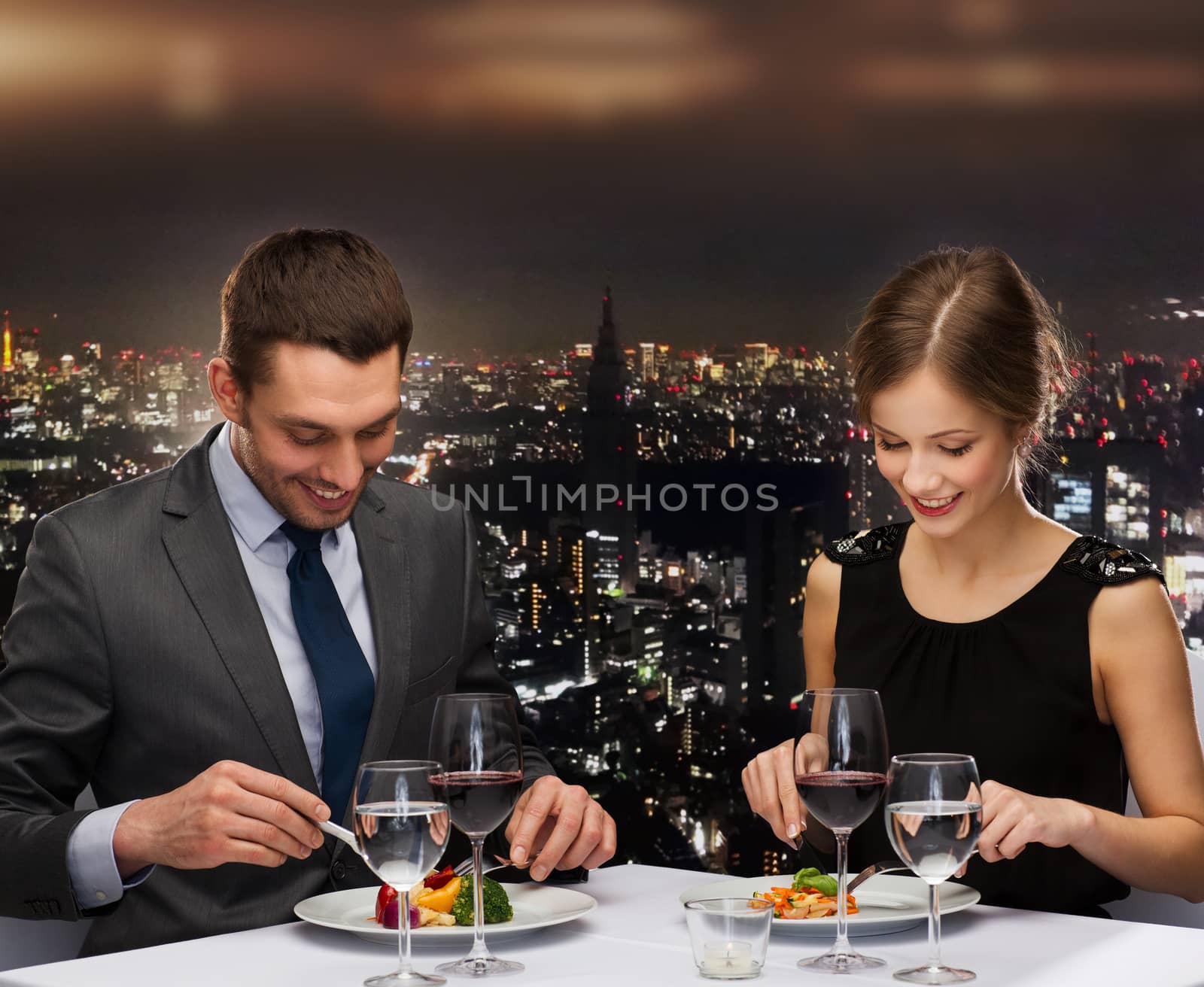 restaurant, couple and holiday concept - smiling couple eating main course with red wine at restaurant