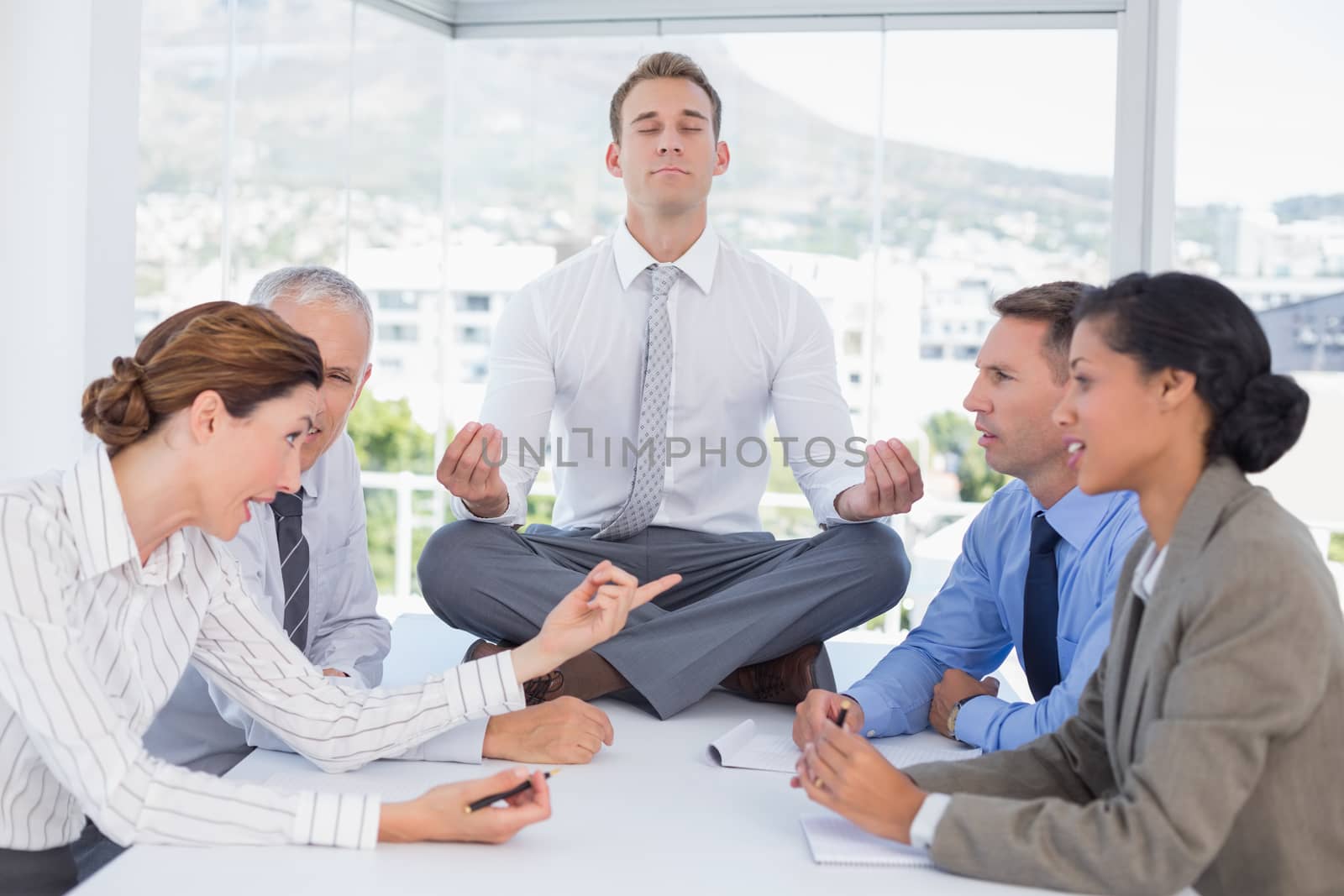 Businessman relaxing on the desk with upset colleagues around by Wavebreakmedia