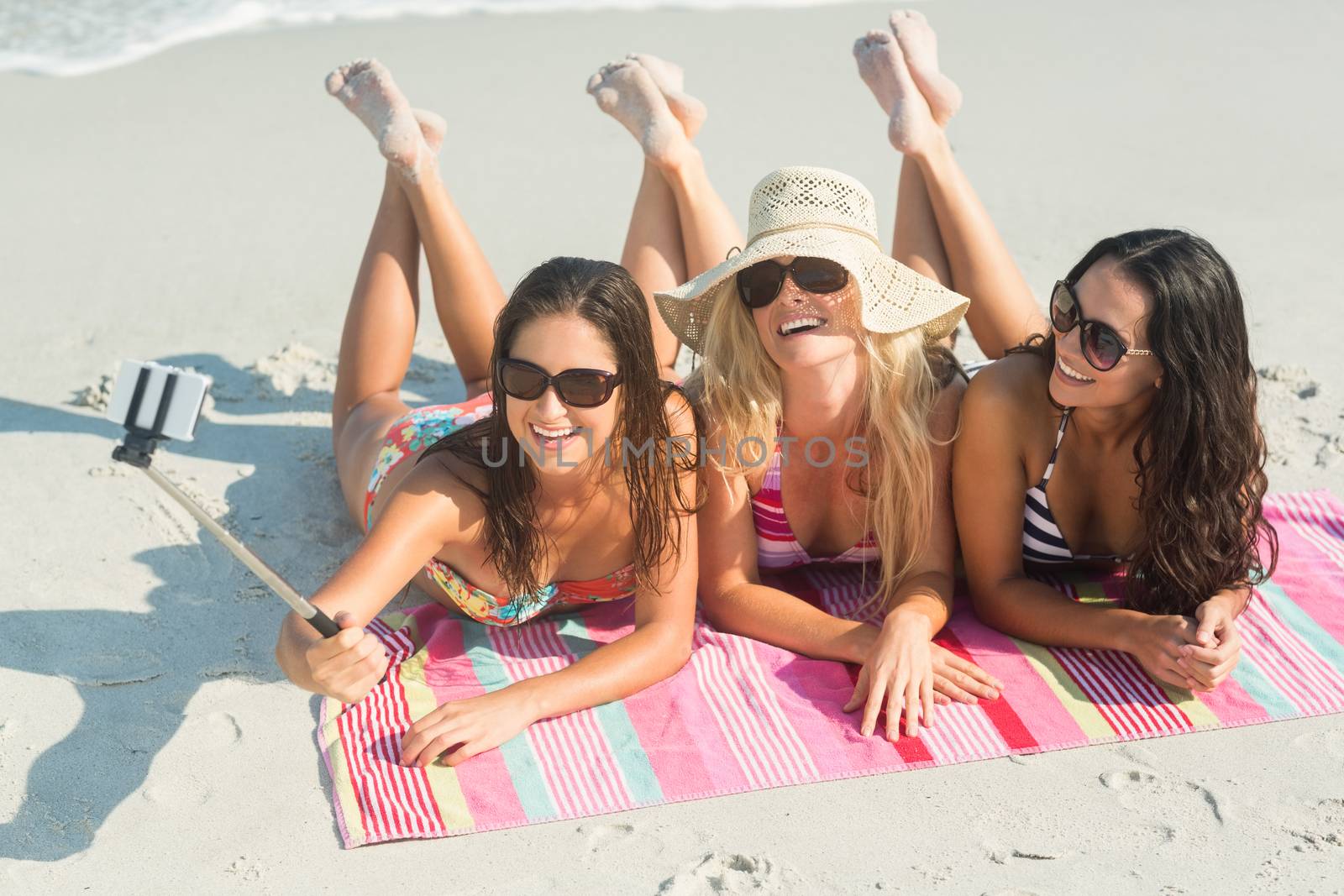 group of friends in swimsuits taking a selfie at the beach