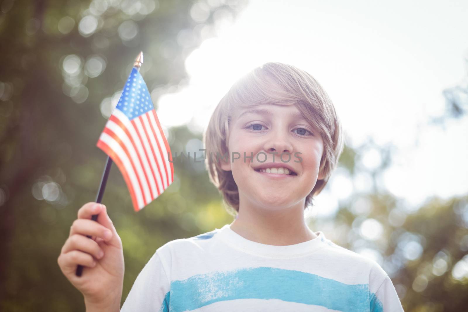 Young boy holding an american flag on a sunny day 