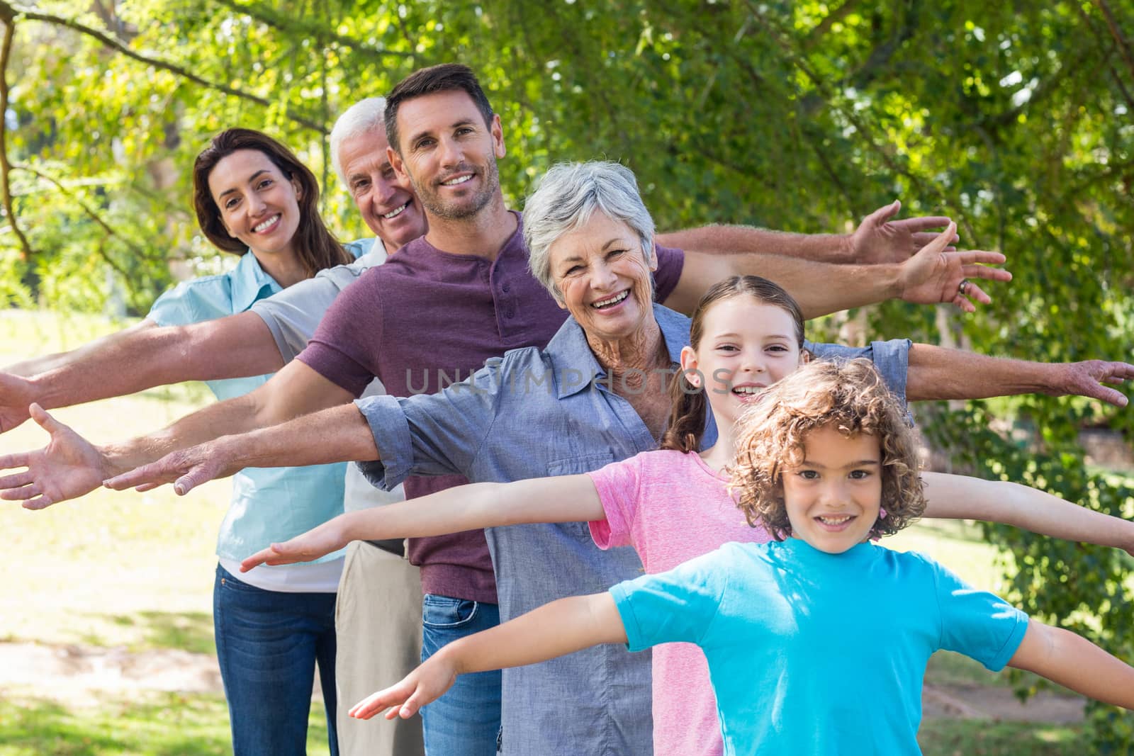 Extended family smiling in the park on a sunny day