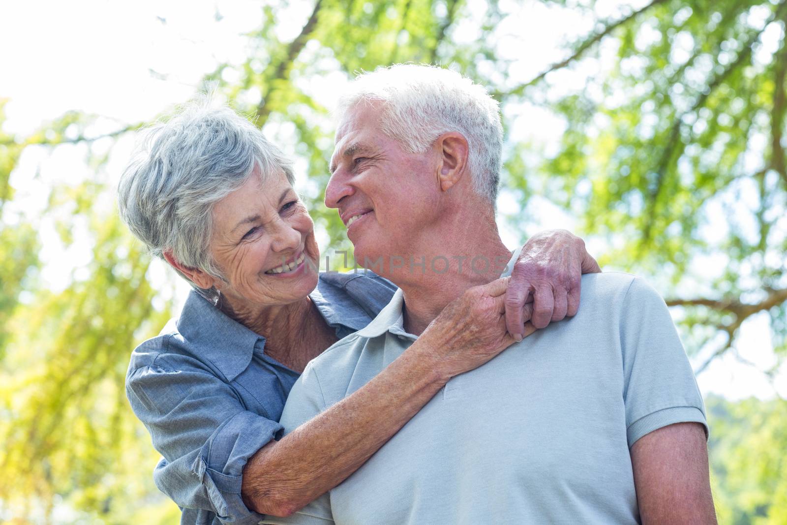 Happy old couple smiling in a park on a sunny day 