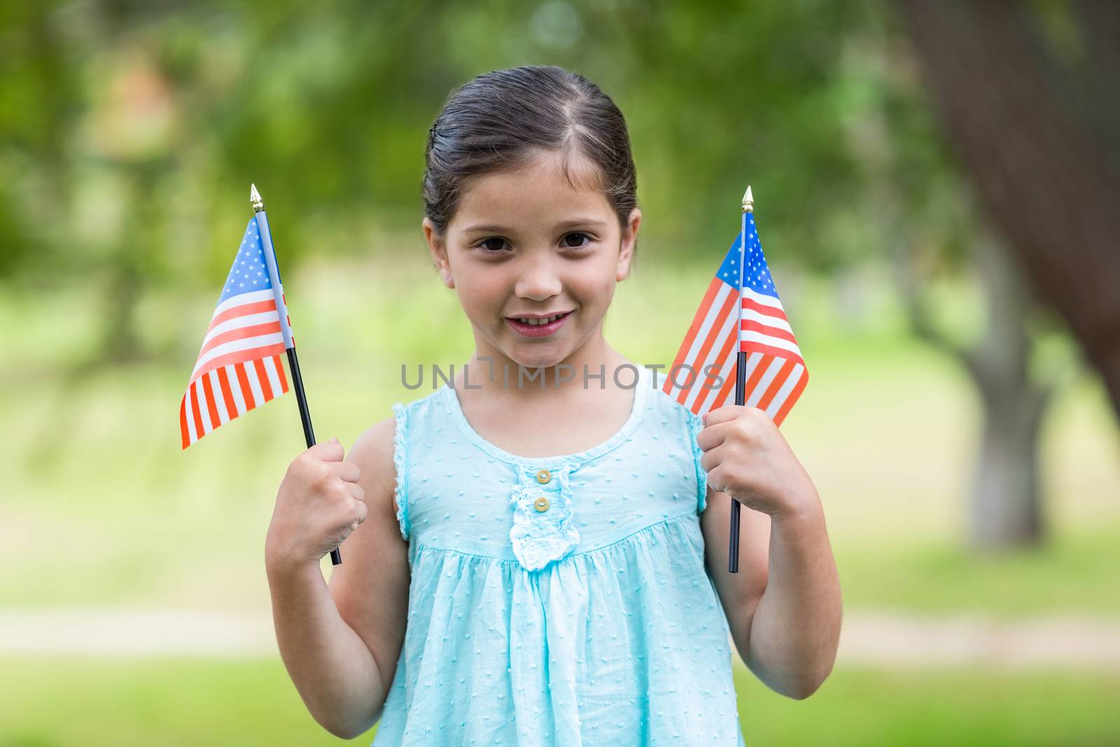 Little girl waving american flag on a sunny day