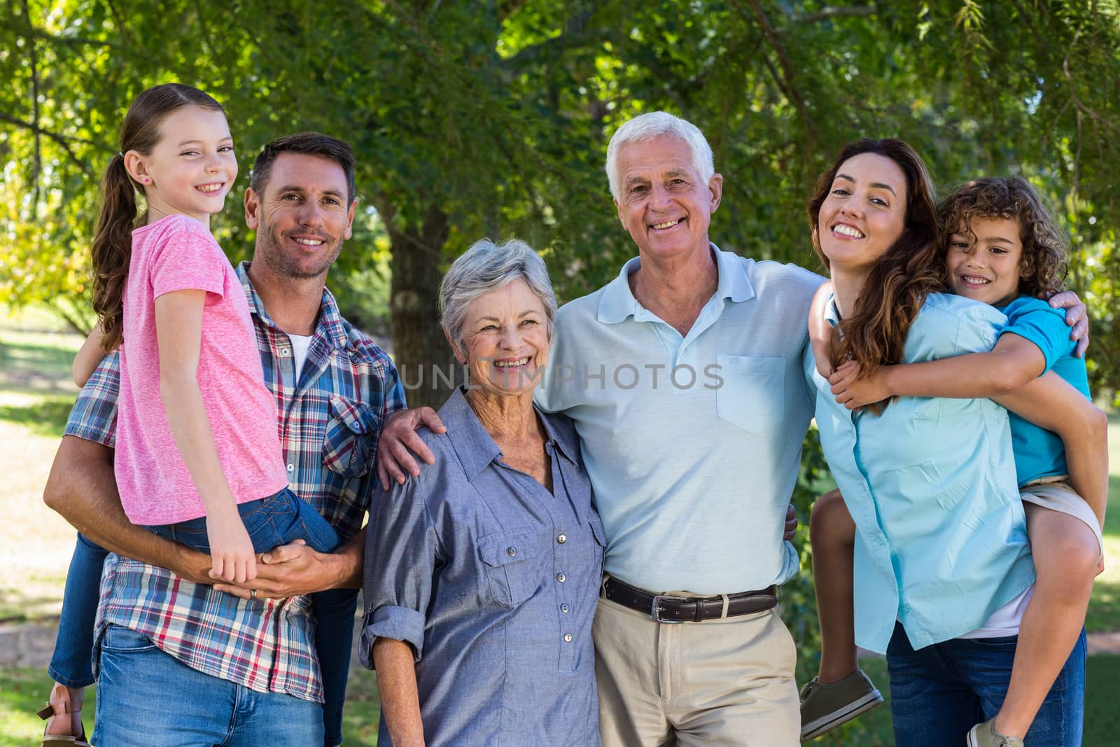 Extended family smiling at the camera on a sunny day