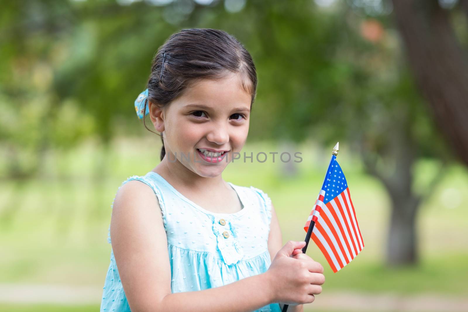 Little girl waving american flag on a sunny day