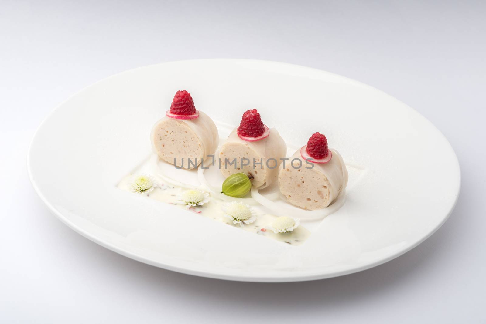 banana rolls with raspberries on a white plate on a white background