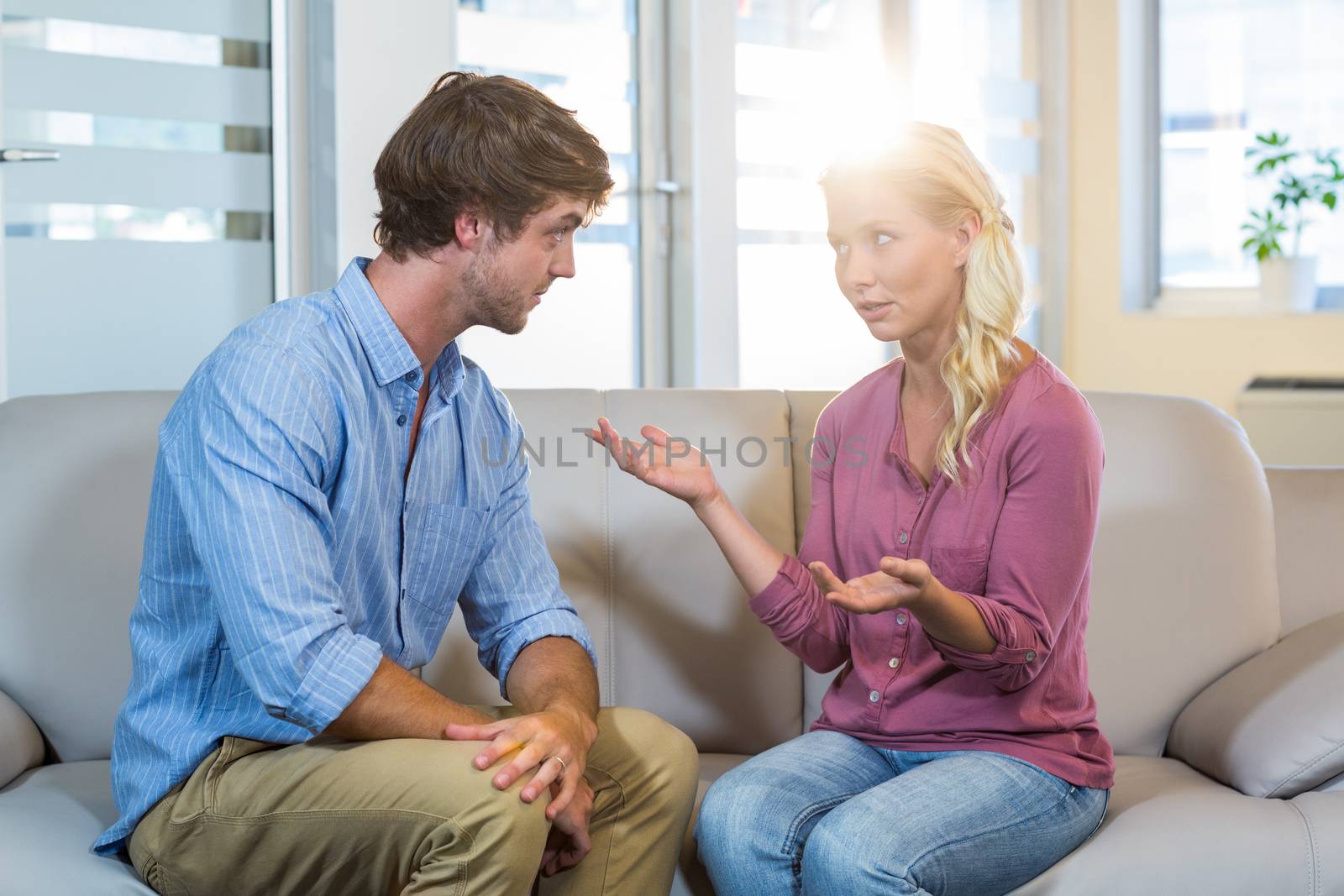 Unsmiling couple talking to each other in the therapist office