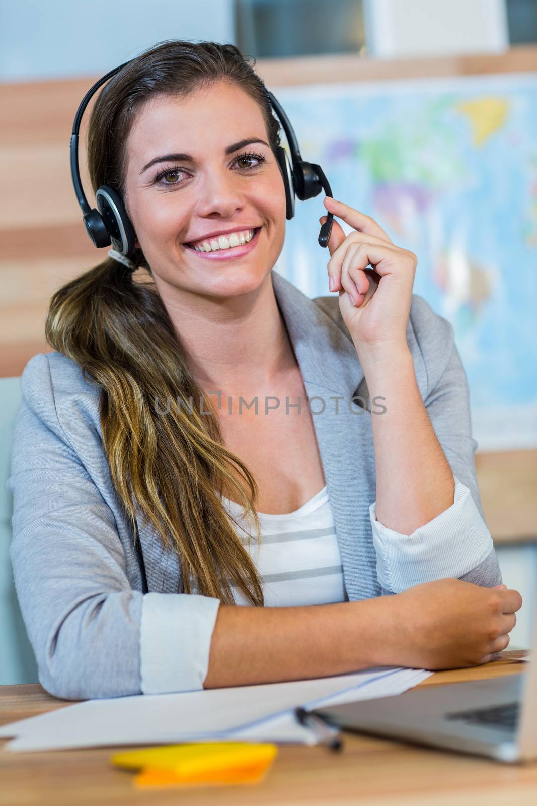 Pretty travel agent smiling at camera in the office