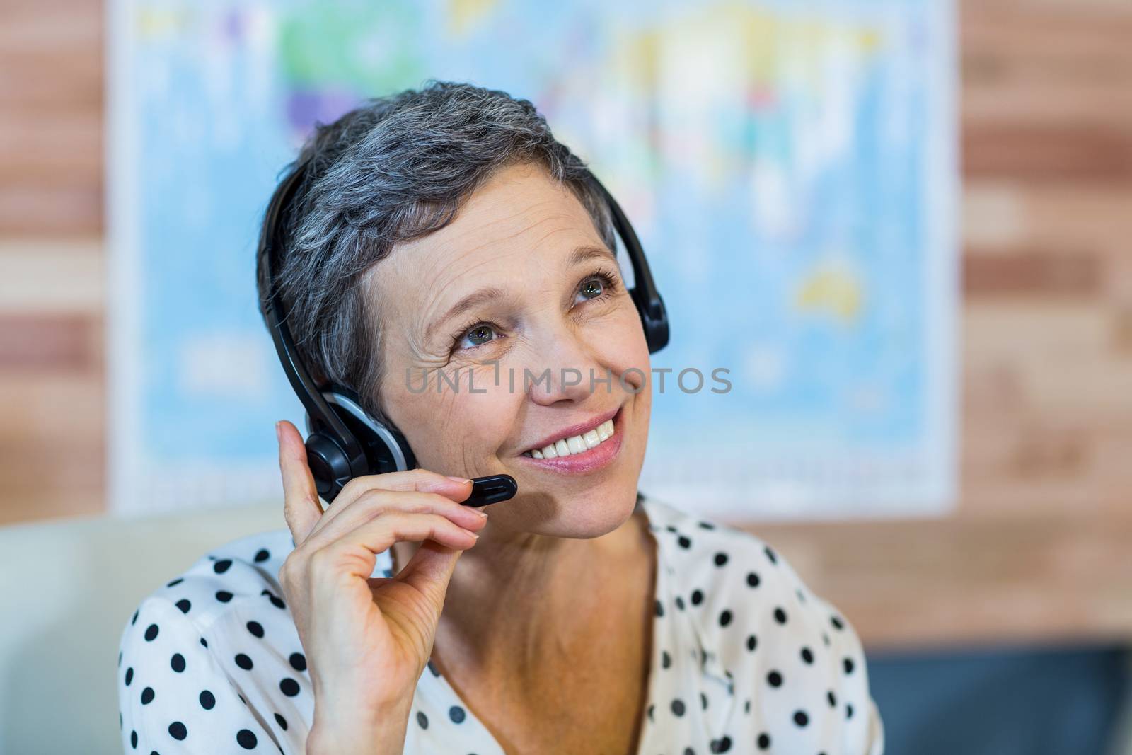 Smiling travel agent sitting at her desk by Wavebreakmedia