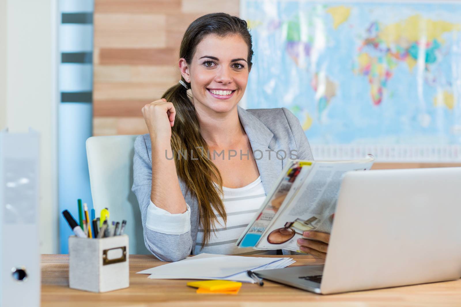 Pretty travel agent reading magazine in the office