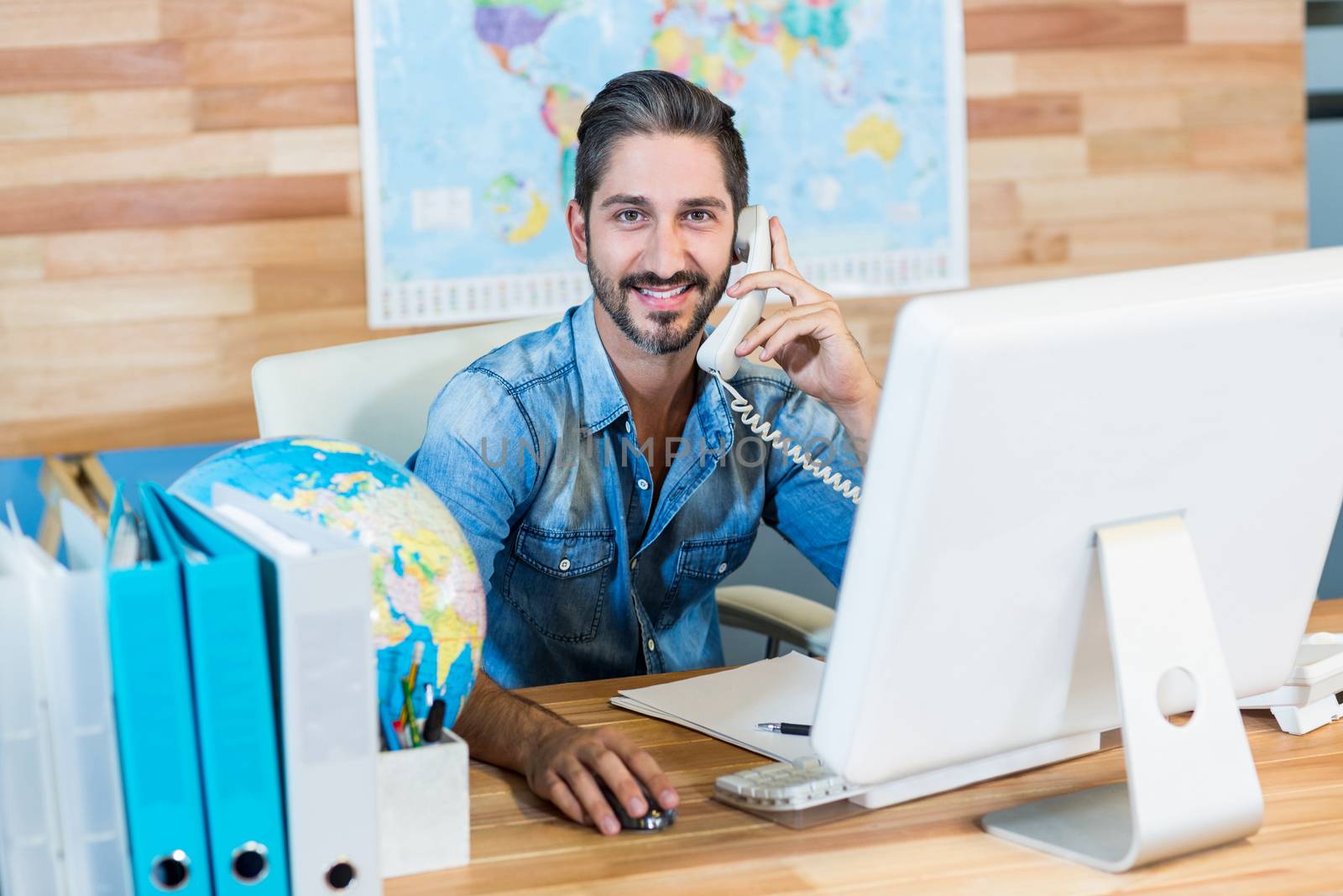 Smiling travel agent having phone call in the office