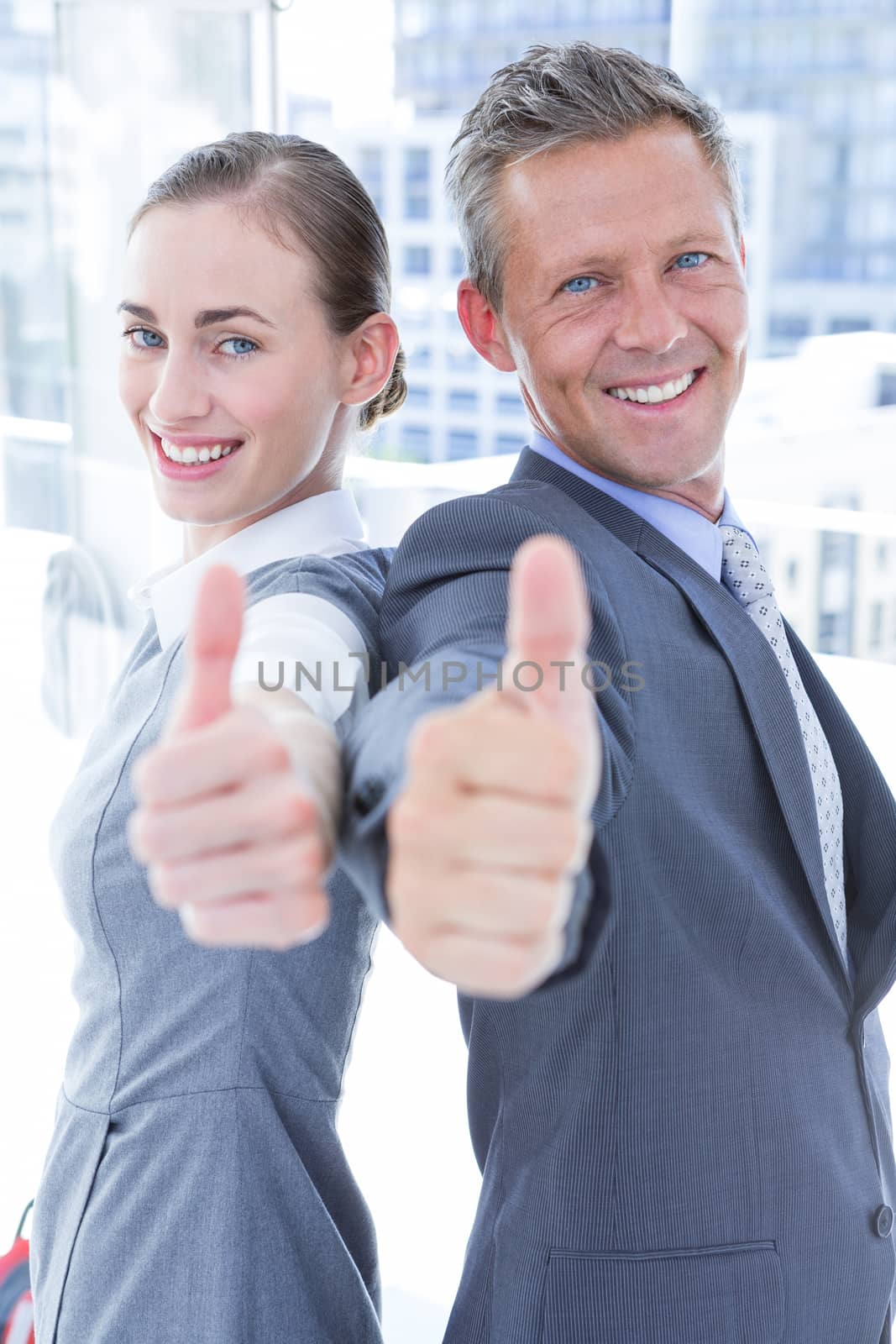 Two business colleagues giving thumbs up in the office