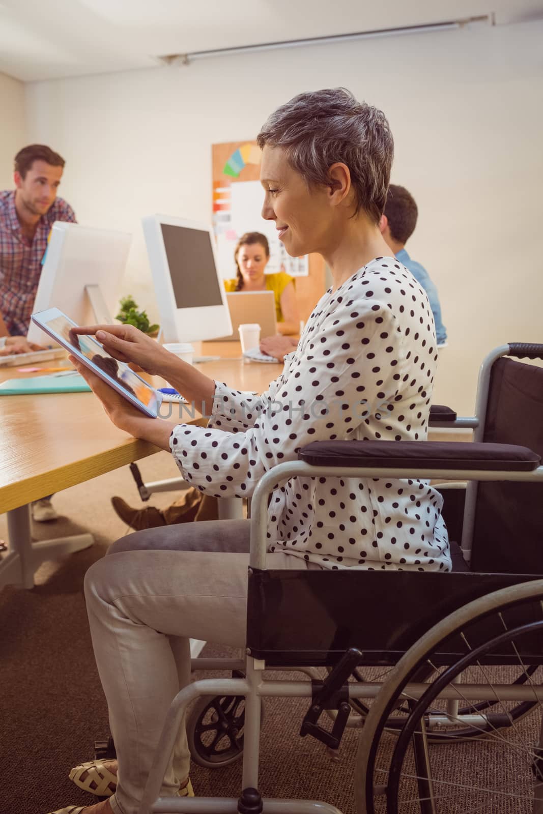 Creative businesswoman in wheelchair using a tablet in the office