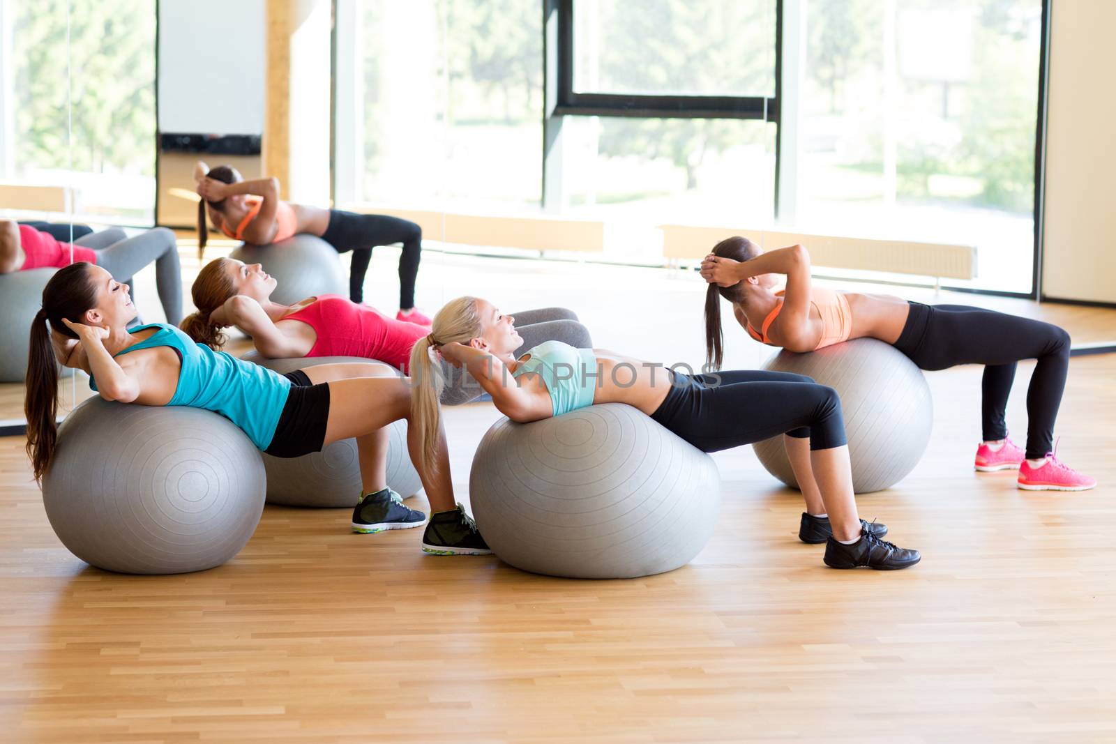 group of smiling women with exercise balls in gym by dolgachov