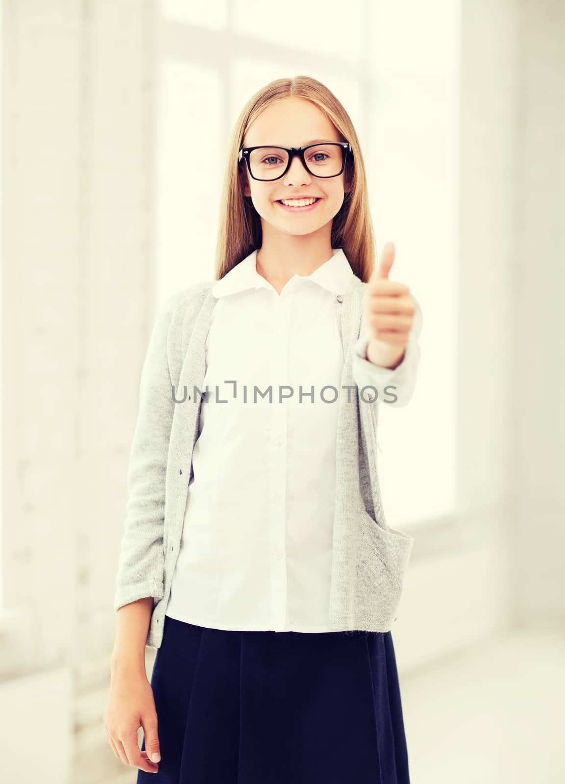 education and school concept - little student girl showing thumbs up at school