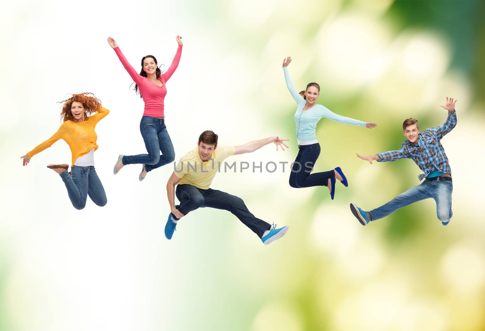 happiness, freedom, ecology, friendship and people concept - group of smiling teenagers jumping in air over green background