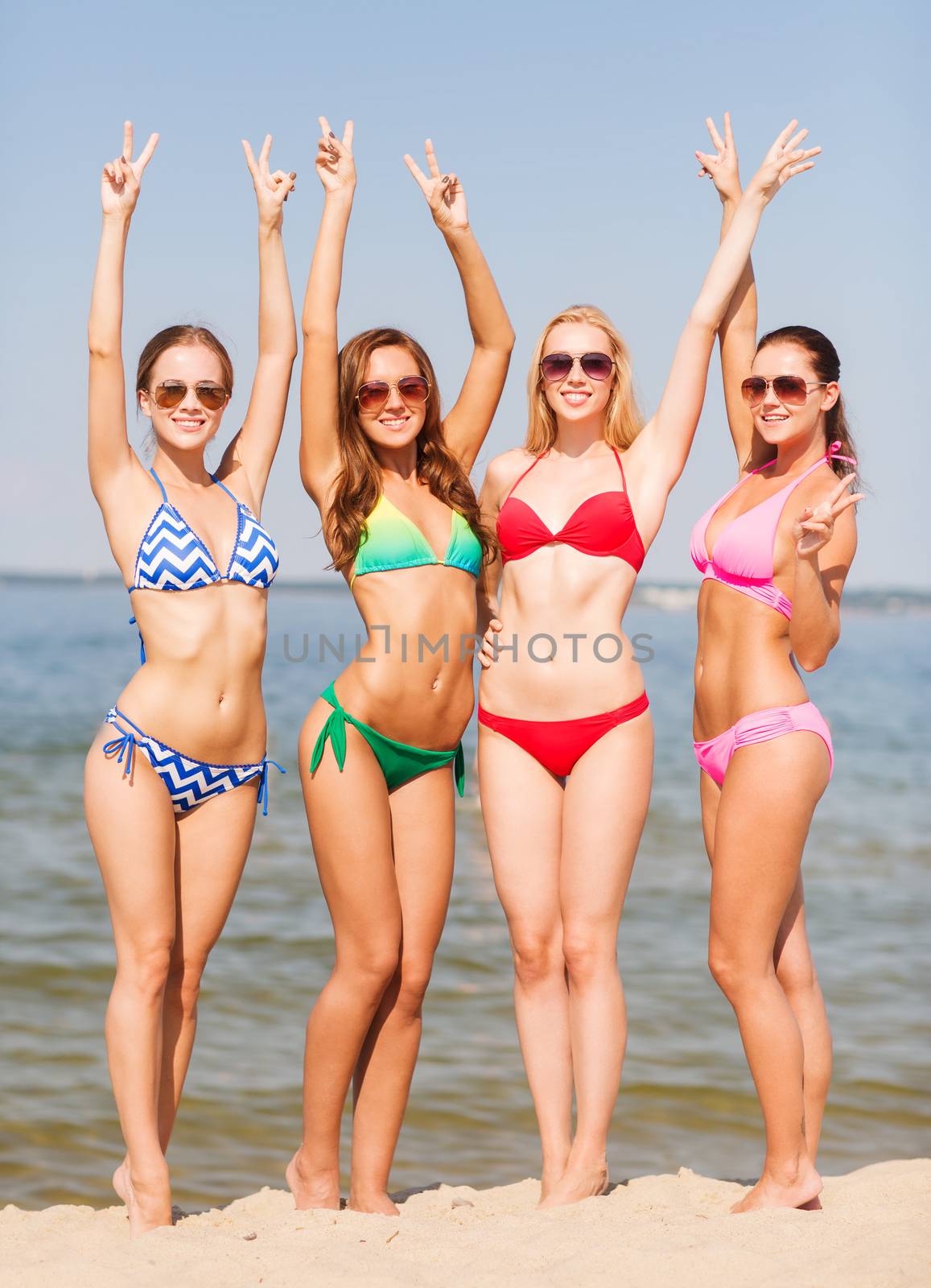 summer vacation, holidays, gesture, travel and people concept - group of smiling young women showing peace or victory sign on beach
