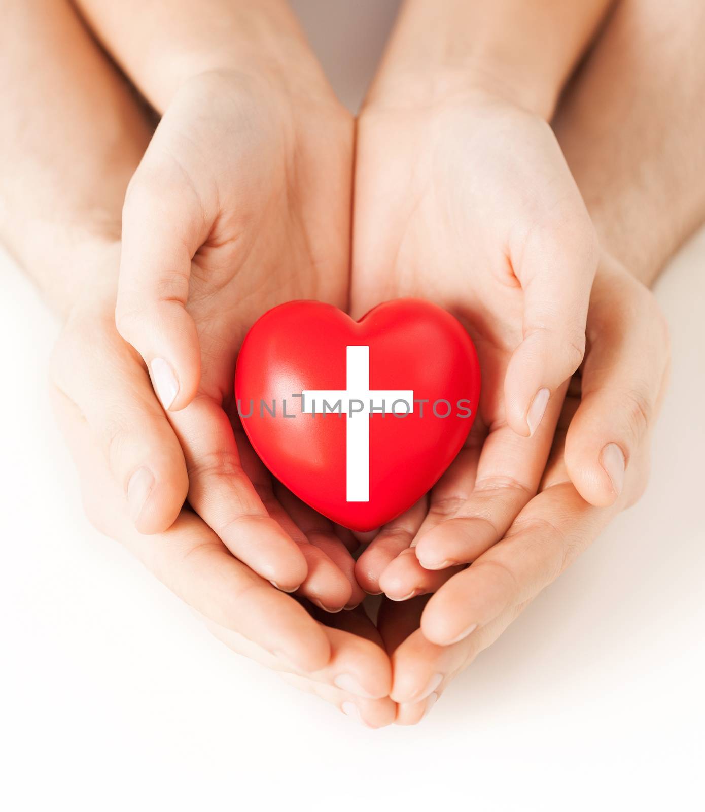 religion, christianity and charity concept - family couple hands holding red heart with christian cross symbol