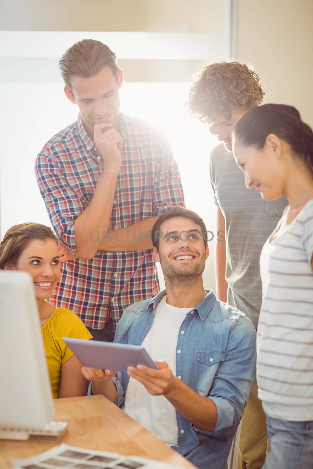 Creative business team gathered around a tablet by Wavebreakmedia