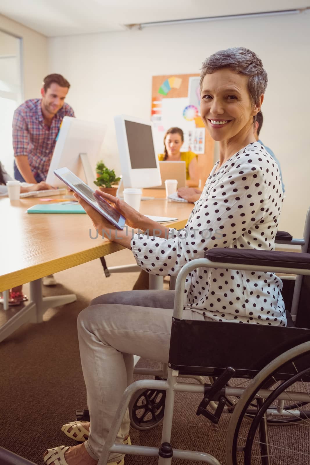 Creative businesswoman in wheelchair using a tablet in the office