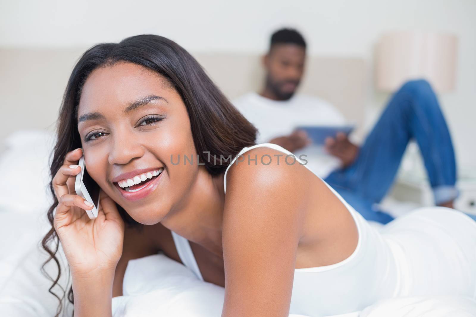 Relaxed couple using technology on bed at home in bedroom