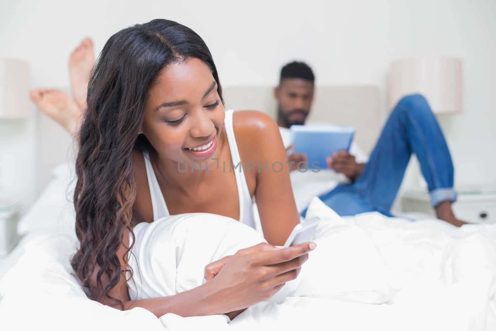 Relaxed couple using technology on bed at home in bedroom