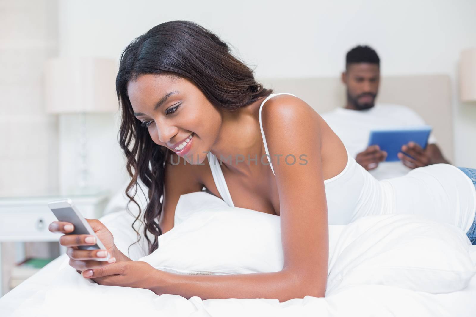 Relaxed couple using technology on bed at home in bedroom