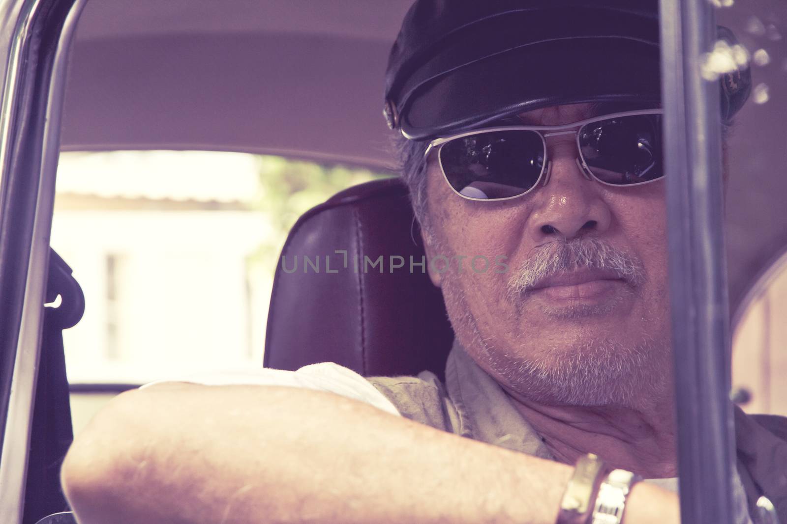 Close up image of older man with glasses driving a car