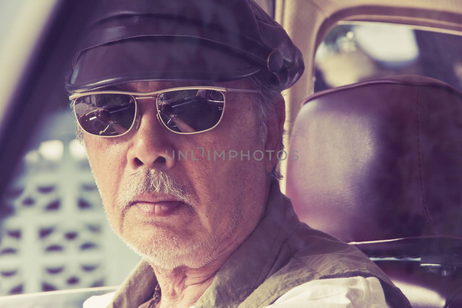 Close up image of older man with glasses driving a car