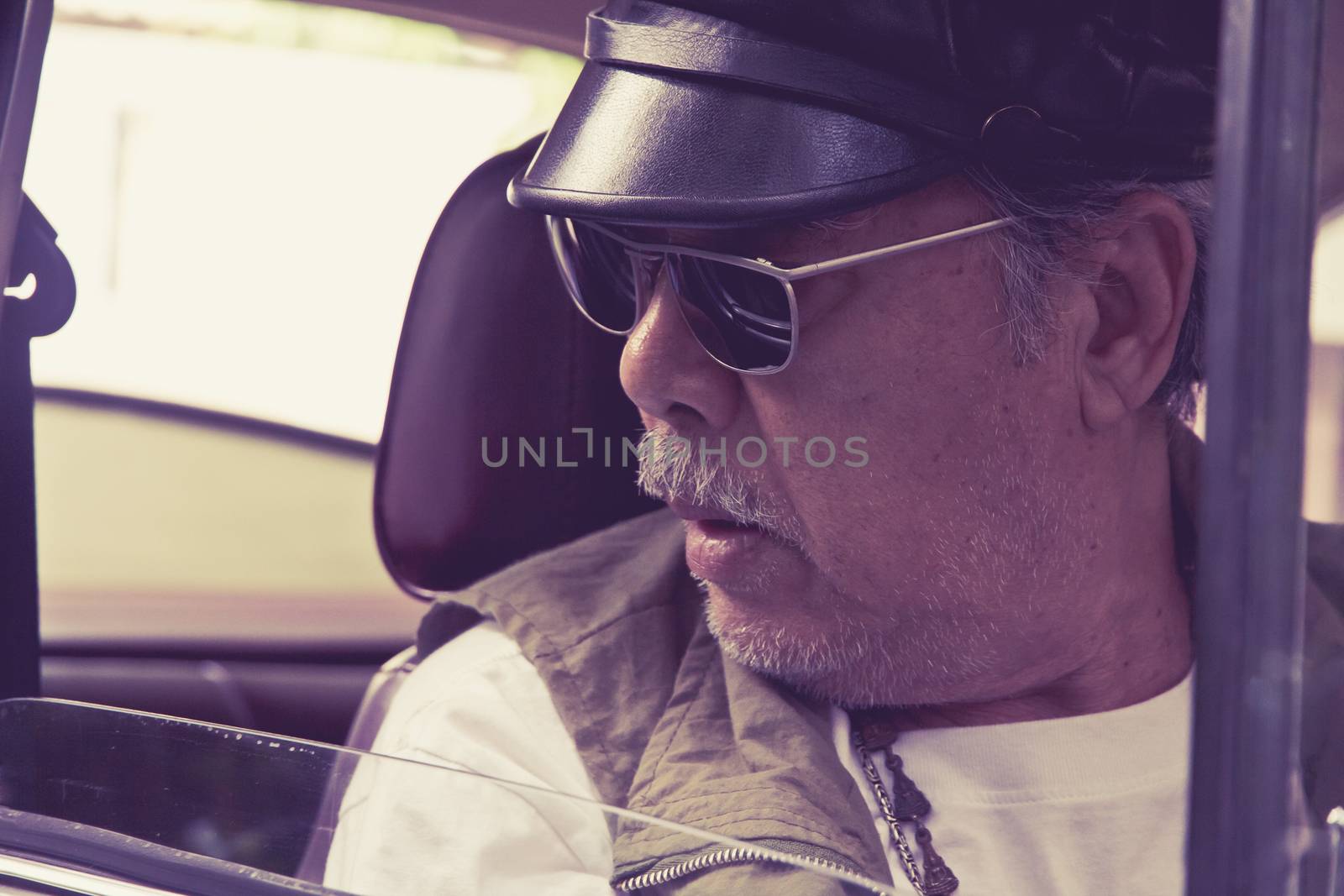 Older man with glasses driving a car by ponsulak