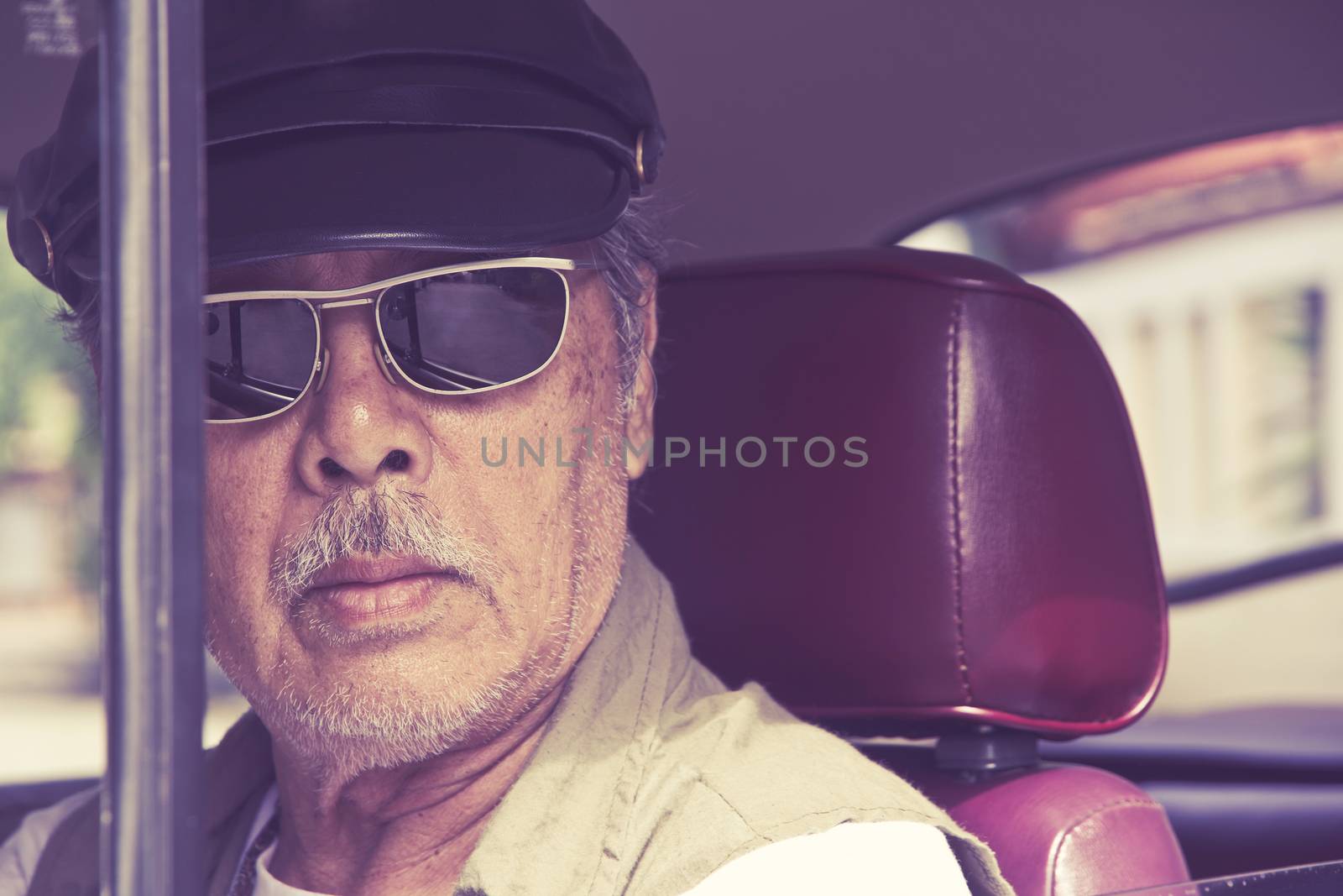 Close up image of older man with glasses driving a car