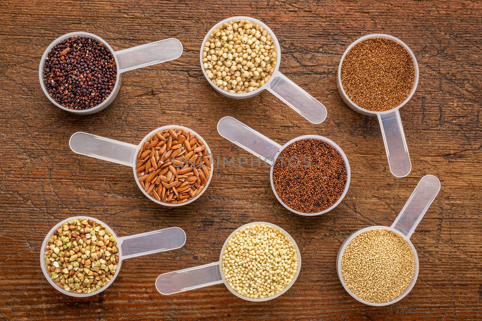 gluten free grains (quinoa, brown rice, kaniwa, amaranth, sorghum, millet, buckwheat, teff) - a set of measuring scoops on a rustic wood